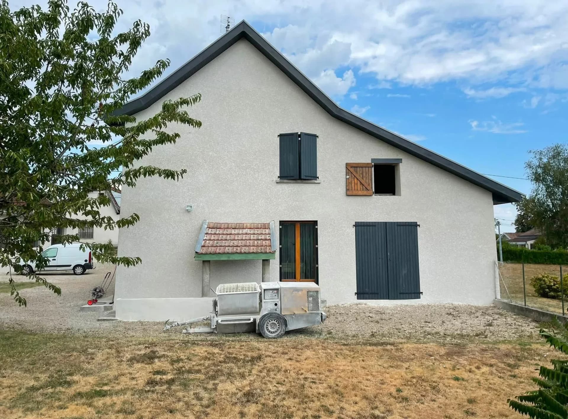 Façade de maison après enduit à la chaux, machine de projection au premier plan